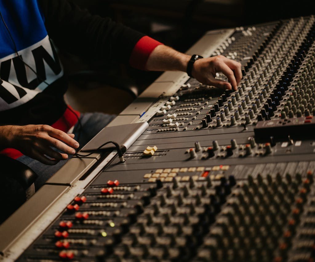 Sound engineer adjusting audio levels on a mixing console in a modern recording studio.